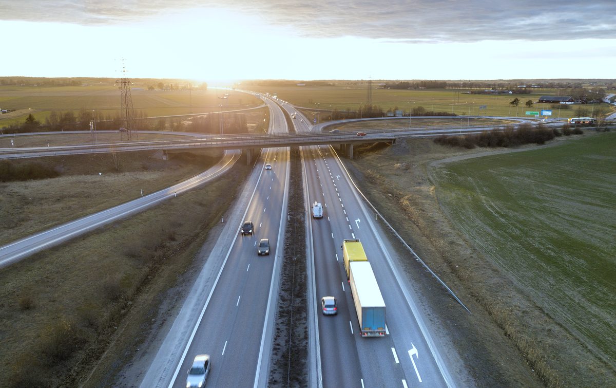 A semi truck on a divided highway at a rural interchange, seen from above