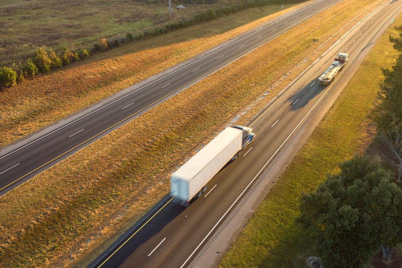 A white box truck on a divided highway at golden hour